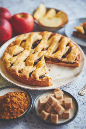Delicious cutted apple pie cake with a fresh red and green apples fruits, brown and powder sugar. Placed on rusty scratched stone table.の写真素材