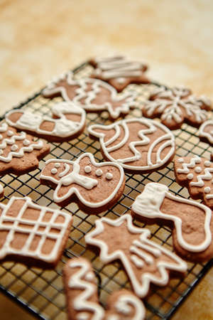 Fresh baked and prepared Christmas shaped gingerbread cookies placed on steel grill frame on a table. View from above.の写真素材