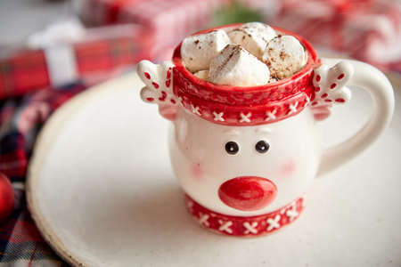 Tasty homemade christmas hot chocolate or cocoa with marshmellows in a red xmas decorative cup. Placed on white wooden background.の写真素材