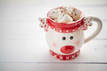 Tasty homemade christmas hot chocolate or cocoa with marshmellows in a red xmas decorative cup. Placed on white wooden background.の写真素材