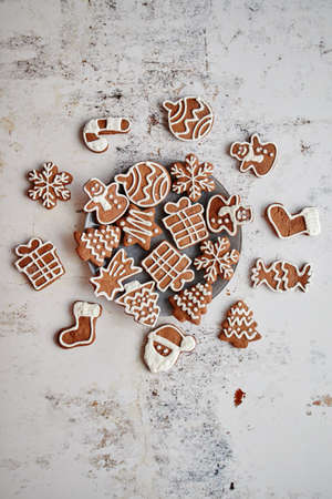 Fresh and tasty Christmas gingerbread cookies placed on white rusty table. Different shapes. Santa claus, snowflake, tree, gift, snowman.の写真素材