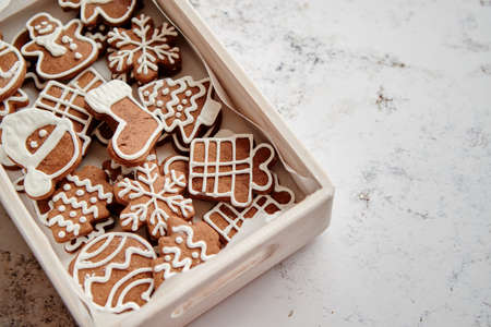 Collection of various shaped gingerbread Christmas cookies placed in white wooden crate. White rusty table. Top view.の写真素材