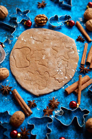 Christmas baking concept. Gingerbread dough with different cutter shapes and spices on sides. Top view on blue rustic background.の写真素材