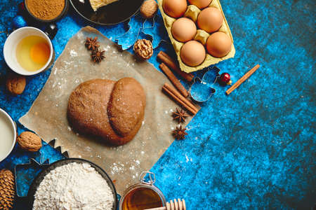 Ready for next step raw gingerbread dough placed among various ingredients. Christmas baking concept. Placed on blue background. View from above.の写真素材