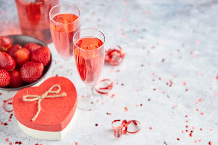 Bottle of rose champagne, two glasses with fresh ripe strawberries and heart shaped boxed gift, placed on stone table for a special romantic occasion or Valentines. With copy spaceの写真素材
