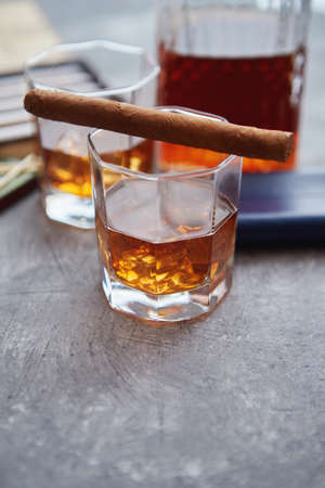 Carafe of Whiskey or brandy, glasses and box of finnest Cuban cigars on an gray stone table. With ice cubesの写真素材