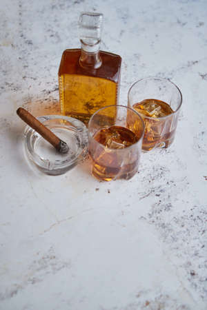 Bottle and glasses of brandy or wiskey and nice big cuban cigar on white rustic backgroundの写真素材