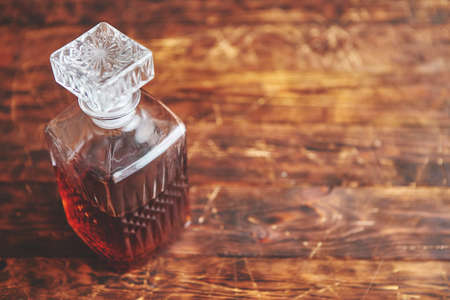 Elegant carafe filled with whiskey, bourbon or rum. Placed on vintage wooden table.の写真素材