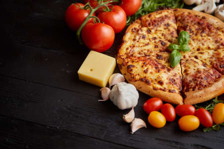 Fresh baked, hot american style pizza with all various ingredients on side. Placed on wooden table....