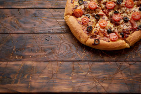 Pizza pepperoni with mozzarella cheese, tomato sauce, salami, black olives, cherry tomatoes. American style pizza on brown rusty wooden table background.の写真素材