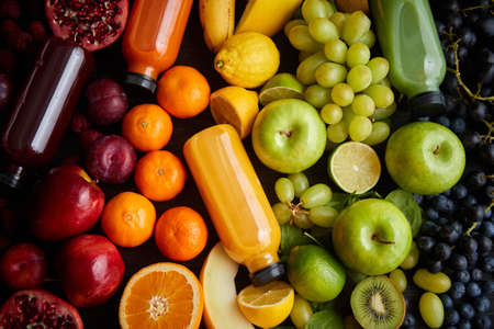 Various healthy fruits and vegetables formed in rainbow style composition. Placed on black wooden table. With bottles on fresh squeezed juice.の写真素材