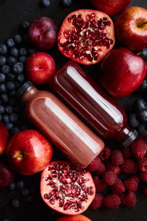 Mix of fresh red and black fruits. With botteled fresh juices. Placed on black wooden table.の写真素材