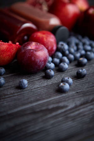 Mix of fresh red and black fruits. With botteled fresh juices. Placed on black wooden table.の写真素材