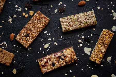 Homemade gluten free granola bars with mixed nuts, seeds, dried fruits on black stone background. Top view.の写真素材