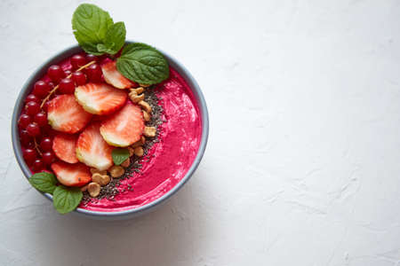 Summer berry smoothie or yogurt bowl with strawberries, red currants and chia seeds on white background. Healthy food for breakfast concept. Close-up, top view, space for text.