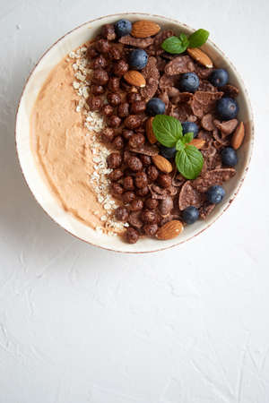 Chocolate and blueberry smoothie or yogurt. With cocoa cornflakes, granola, mint leaves and almonds....