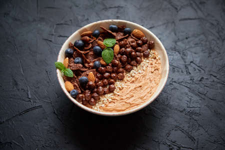 Chocolate and blueberry smoothie or yogurt. With cocoa cornflakes, granola, mint leaves and almonds....
