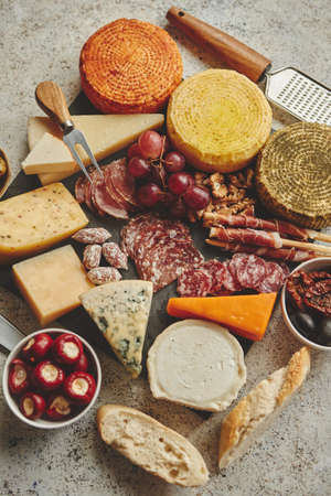 Delicious mix of different snacks and appetizers. Spanish tapas or italian antipasti on a black stone plate. View from above. Placed on stone table.の写真素材