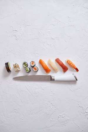Various sushi rolls with Japanese knife on white stone slate background. With copy space for text. Top view.の写真素材