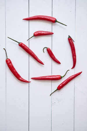 Red hot chili peppers pattern isolated on white wooden table background. Top view. Flat layの写真素材