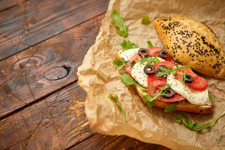 Delicious fresh Bruschetta with tomato, basil, black olives and mozarella cheese. Placed on brown wooden table. Top view.の写真素材