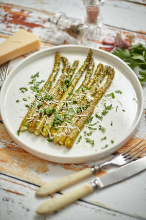 Roasted asparagus with parmesan cheese and parsley. Healthy spring food concept. View from above. On white wooden table.の写真素材