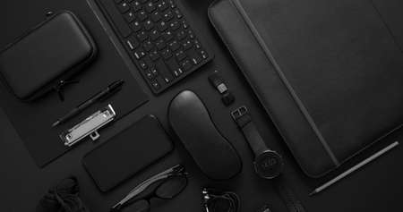 Business concept. Flat lay composition with various black gadgets. Computer keyboard, smartphone, leather wallet, glasses on dark black surface. Business people items. Top view.の写真素材