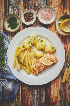 Fresh and tasty baked salmon served with young boiled potatoes and yellow bean. Sprinkled with aromatic dill. On a plate. Top View.の写真素材