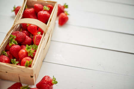 Wooden container with fresh red strawberries. Placed on white table. Top view.の写真素材