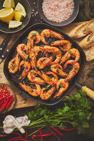 Tasty appetizing roasted shrimps prawns with spices on pan with ingredients on rusty background. Top View, flat lay. Background Seafood Kitchen Conceptの写真素材