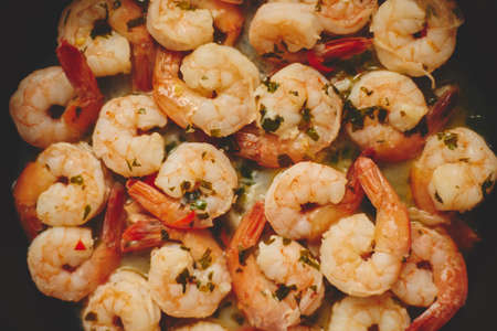 Baby shrimps with parsley and garlic are cooked in a pan, top view, flat lay, close-up.の写真素材