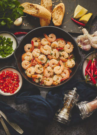 Fried baby Shrimps served on iron pan and fresh herbs and ingredients. Top view, flat lay.の写真素材