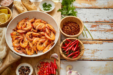 Top view of prawns shrimps roasted on pan with herbs placed on rustic wooden kitchen table. Delicious healthy seafood concept.の写真素材
