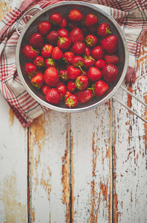 Freshly harvested strawberries. Metal colander filled with juicy fresh ripe red strawberries on an...