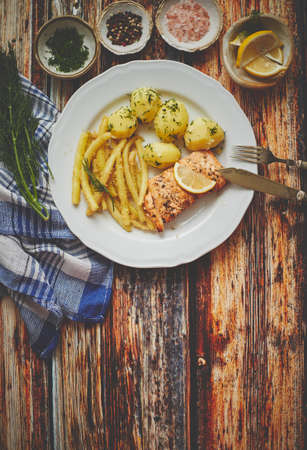 Fresh and tasty baked salmon served with young boiled potatoes and yellow bean. Sprinkled with aromatic dill. On a plate. Top View.の写真素材