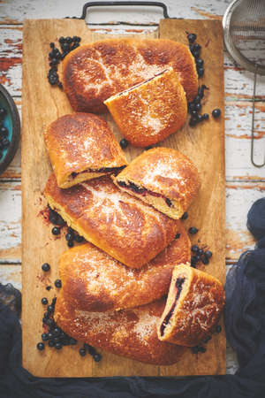 Tasty homemade blueberry bun stuffed with fresh forrest fruits. Traditional polish bun called jagodzianka. Placed on wooden chopping board. Top view, flat lay.の写真素材