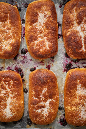 Delicious hot homemade buns stuffed with blueberry on a baking tray. Flat lay, top view.
