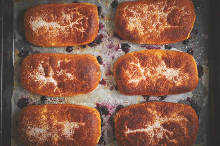 Delicious hot homemade buns stuffed with blueberry on a baking tray. Flat lay, top view.の写真素材