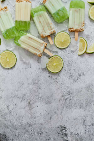 Delicious lime and cream homemade ice creams placed with ice cubes on gray stone backdrop. Flat lay, top view with copy spaceの写真素材