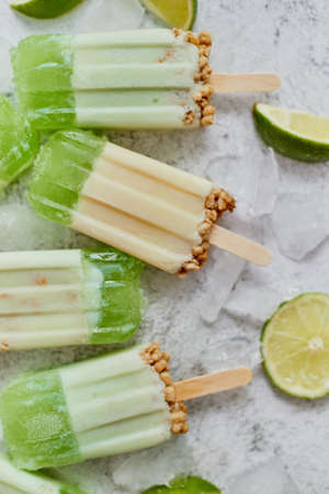 Lime and cream homemade ice creams placed with ice cubes on gray stone backdrop. Flat lay, top view.の写真素材