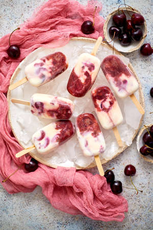 Fresh cream and cherry homemade ice cream placed on white ceramic plate with fruits and textile. Top view, flat lay.の写真素材