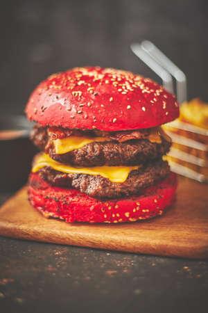 Palatable burger with meat patties and red bun placed on board in cafeの写真素材