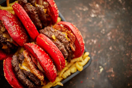 Set of four homemade giant double becon cheese burgers. Served with french fries on wooden board. Rustical background. Fast food concept.の写真素材
