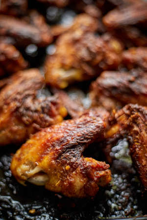 Grilled chicken wings in spices in black metal baking tray on stone table. Top viewの写真素材