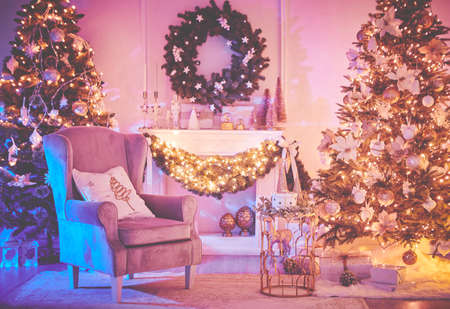 Christmas interior concept. With fireplace, armchair, pine tree, wrapped gifts, lightsの写真素材