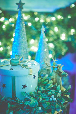 Colorful christmas ornaments and decorations placed on small table with lights in backgroundの写真素材