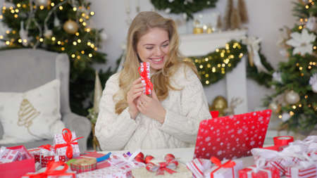 Happy young woman having video chat on laptop in christmas decorated living roomの写真素材