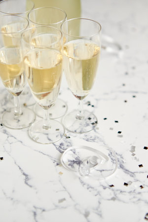 Champagne glasses and bottle placed on white marble backgroundの写真素材