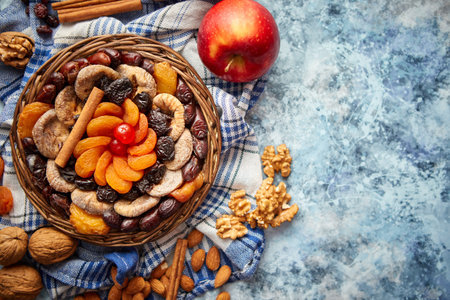 Composition of dried fruits and nuts in small wicker bowl placed on stone tableの写真素材