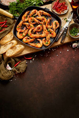 Grilled prawns in cast iron grilling pan with fresh lemon, parsley, chili, garlic white wine sauceの写真素材